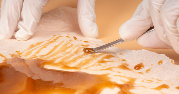 A person wearing white gloves working on BHO extration without a vacuum.